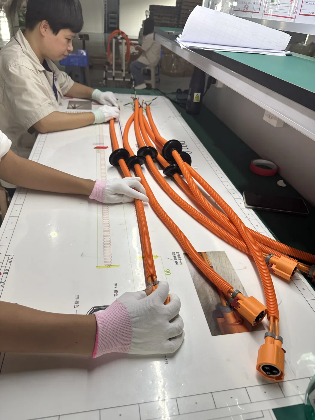 Operator assembling orange high-voltage wiring harnesses