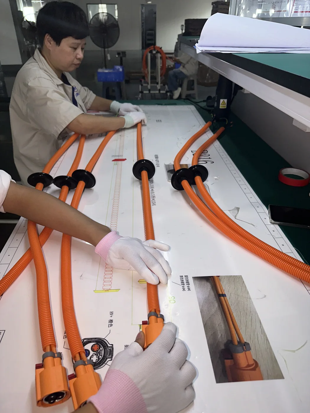 Operator aligning high-voltage wiring harness branches to a work instruction